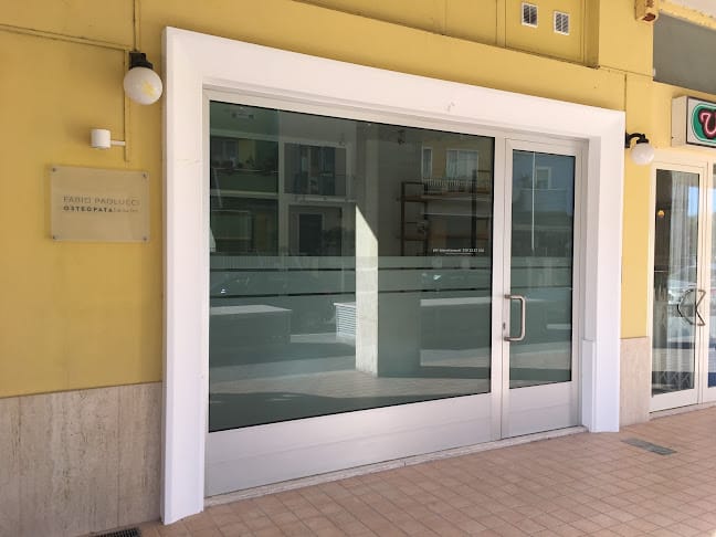 Picture of the entrance of a clinic, Big window and entrance door. The walls are yellow and the picture has been taken from the street