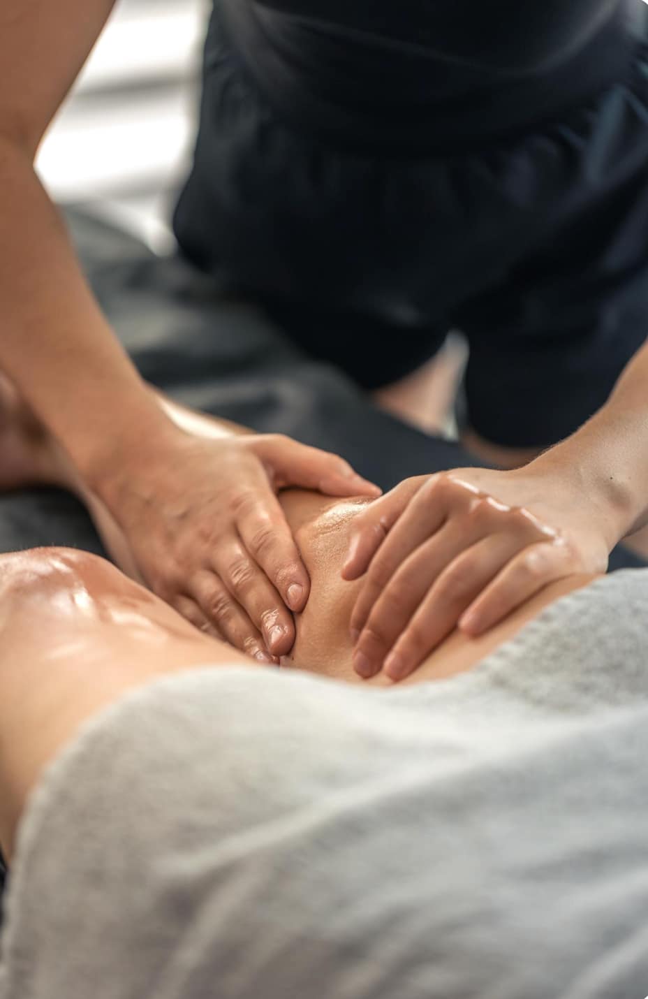 Picture in color
It is a close up where you can see a person massaging the leg and knee of the client. There is a grey towel
The body is oily